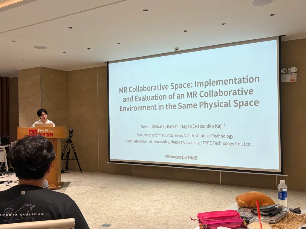 学会会場の演台で「MR Collaborative Space: Implementation and Evaluation of an MR Collaborative Environment in the Same Physical Space」と題したスライドを表示して発表を始める登壇者